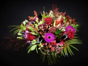 Een prachtig boeket met verschillende bloemen zoals rozen in de kleuren roze, paars, rood en groen.