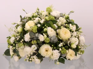 Een rouwstuk met bloemen in de kleuren wit en groen.
