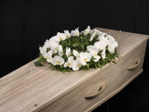 Circle of life, een rouw bloemstuk op een kist met bloemen in witte orchidee bloemen in de vorm van een cirkel, gemaakt door Bloeibloemen.nl