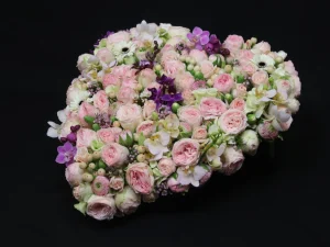 Rouw bloemstuk Hart of pastel. Een bloemstuk in de vorm van een hart, met roze, witte en paarse bloemen. Gemaakt door Bloeibloemen.nl
