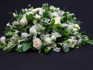 Rouw bloemstuk White Tears. Een groot bloemstuk met verschillende witte bloemen, afgewerkt met groen. Gemaakt door Bloeibloemen.nl