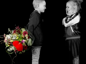 Een jongen die een meisje een boeket bloemen geeft van Bloeibloemen.nl. In het midden van het boeket zit een groot rood hart.