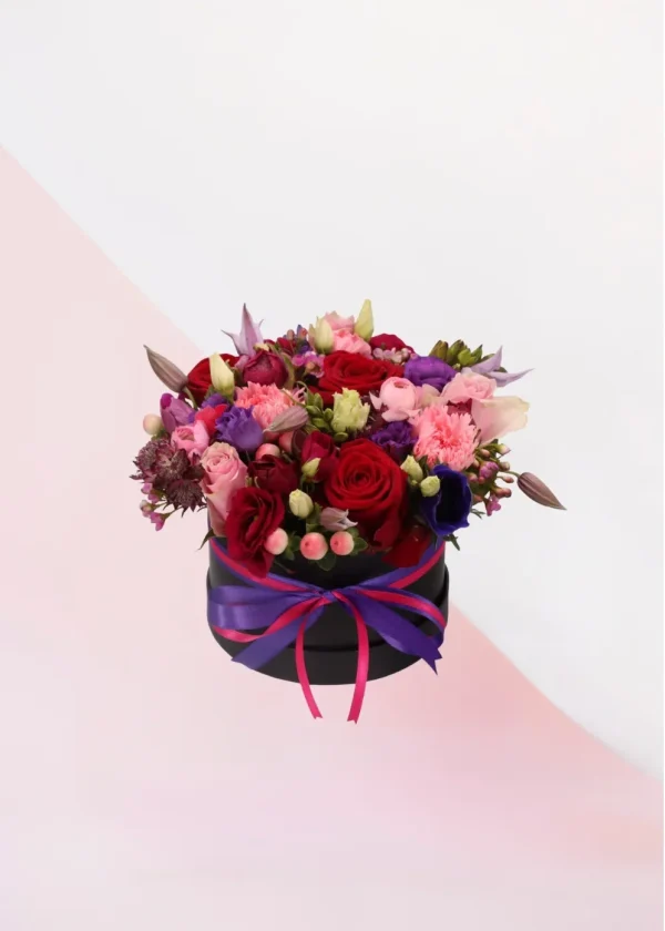 Flower Box Funky, een box met verschillende bloemen in de kleuren roze, paars en wit en rode rozen gestoken in een blok oase. Deze rozen zitten in een zwarte box.