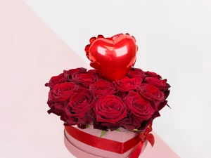 Flowerbox rozen hart klein. Een roze box met daarin allemaal rode rozen gestoken in een blok oase. In het midden zit een kleine ballon in de vorm van een hart. Bloemen voor Valentijnsdag