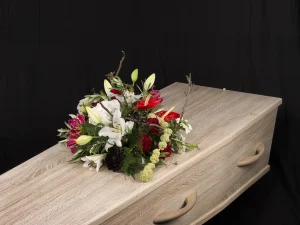 Red and white, een rouw bloemstuk op een kist met bloemen in de kleuren wit, groen en rood, gemaakt door Bloeibloemen.nl