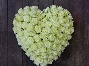 Roses from the heart, een rouw bloemstuk op een kist witte rozen in de vorm van een hart, gemaakt door Bloeibloemen.nl