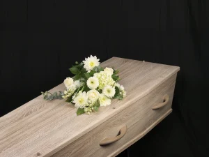 Rouwboeket white, een kleiner bloemstuk met verschillende witte bloemen op een kist, gemaakt door Bloeibloemen.nl