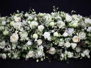 White simplicity, een rouw bloemstuk met verschillende witte bloemen, afgewerkt met groen. Dit is een langwerpig en hoog rouwstuk, gemaakt door Bloeibloemen.nl