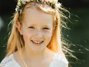 Een bruidsmeisje met een witte jurk aan en een bloemenhaarband in haar haar