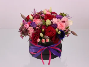 Flowerbox Funky, een box met verschillende bloemen in de kleuren roze, paars en wit en rode rozen gestoken in een blok oase. Deze rozen zitten in een zwarte box.