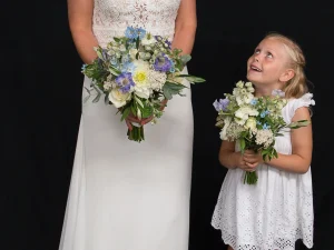 Een bruid en een bruidsmeisje allebei met een bruidsboeket met witte en paarse bloemen in hun handen.