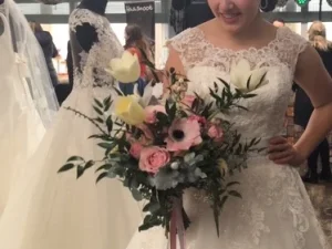 Een bruid met bruidsboeket loose in haar handen. Een groot bruidsboeket met verschillende bloemen in de kleuren wit, roze en groen.