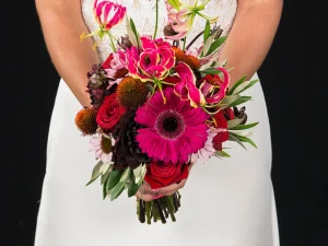 Pasion pink, een close up foto van een bruidsboeket met verschillende bloemen in de kleuren donker roze en rood.