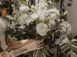 Een heel groot boeket bloemen die iemand vasthoudt. De bloemen zijn wit met groen.