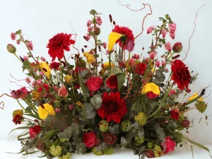 Warm spring flowers. Een bloemstuk voor een begrafenis met verschillende soorten bloemen in de kleuren rood, geel en roze.