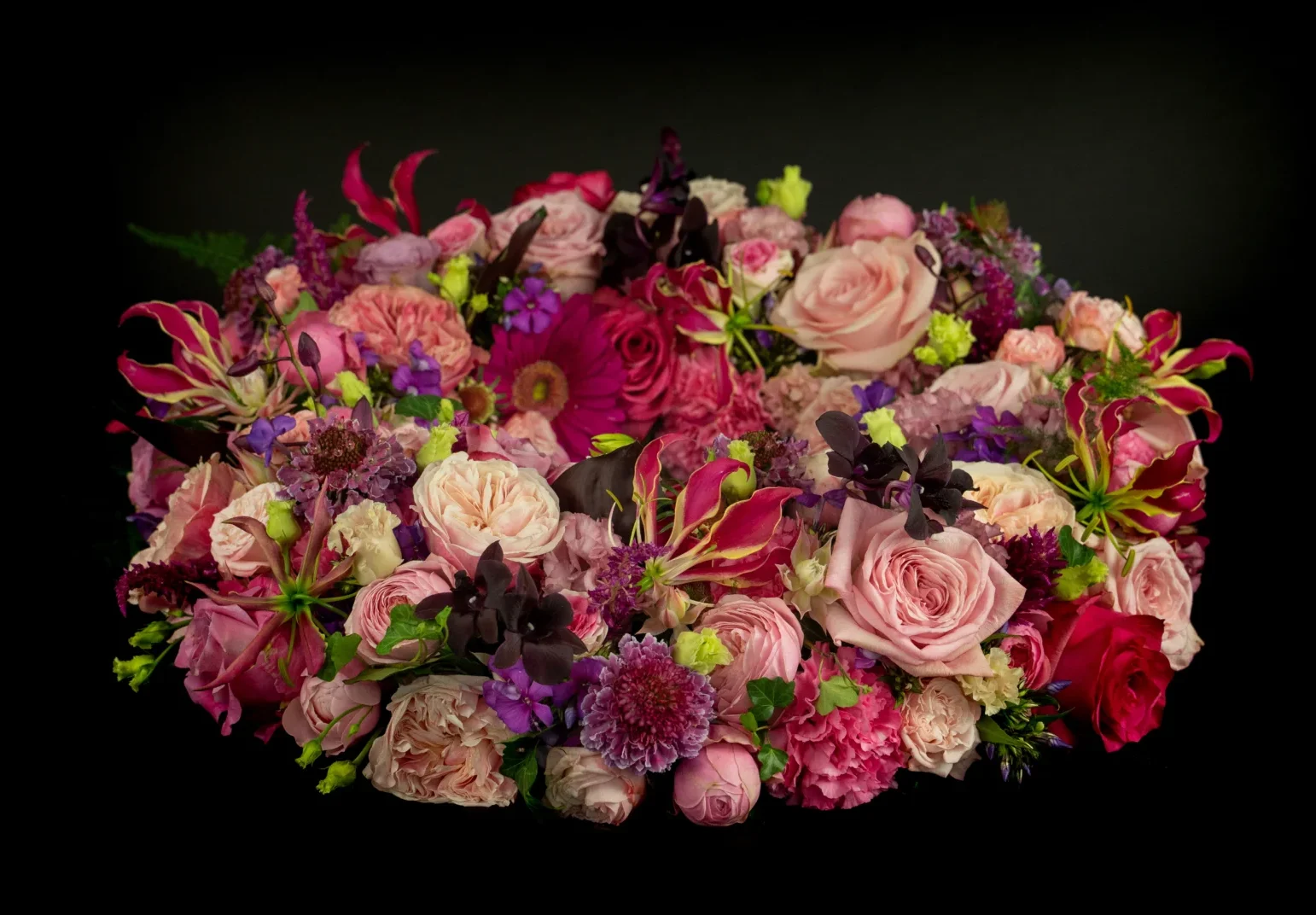 Een rouwkrans met bloemen voor een begrafenis in de kleuren roze, rood, paars en geel.