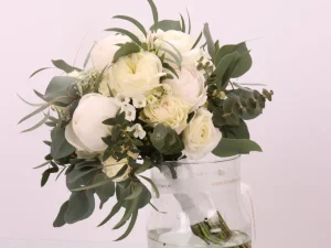 Bruidsboeket Just white een prachtig boeket met verschillende witte bloemen, met toegevoegd groen en een wit lint waarmee de bloemen zijn gebundeld.