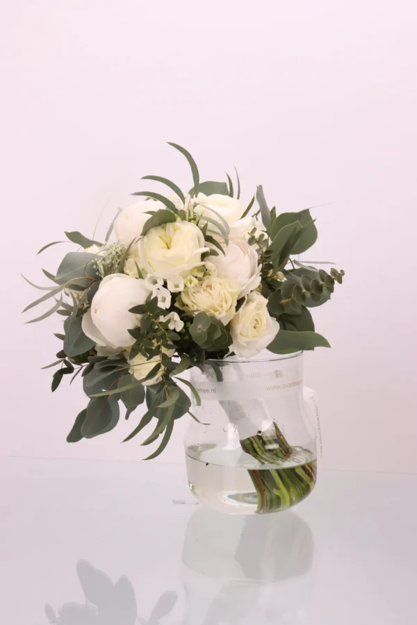 Bruidsboeket Just white een prachtig boeket met verschillende witte bloemen, met toegevoegd groen en een wit lint waarmee de bloemen zijn gebundeld.