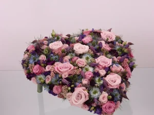 Een prachtig hart met bloemen in paarse tinten. Dit is een rouwstuk.
