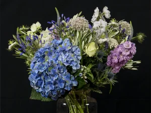 Boeket Flower bomb van Bloeibloemen.nl. Een boeket bloemen in verschillende kleuren, onder andere blauw, paars, groen en wit.