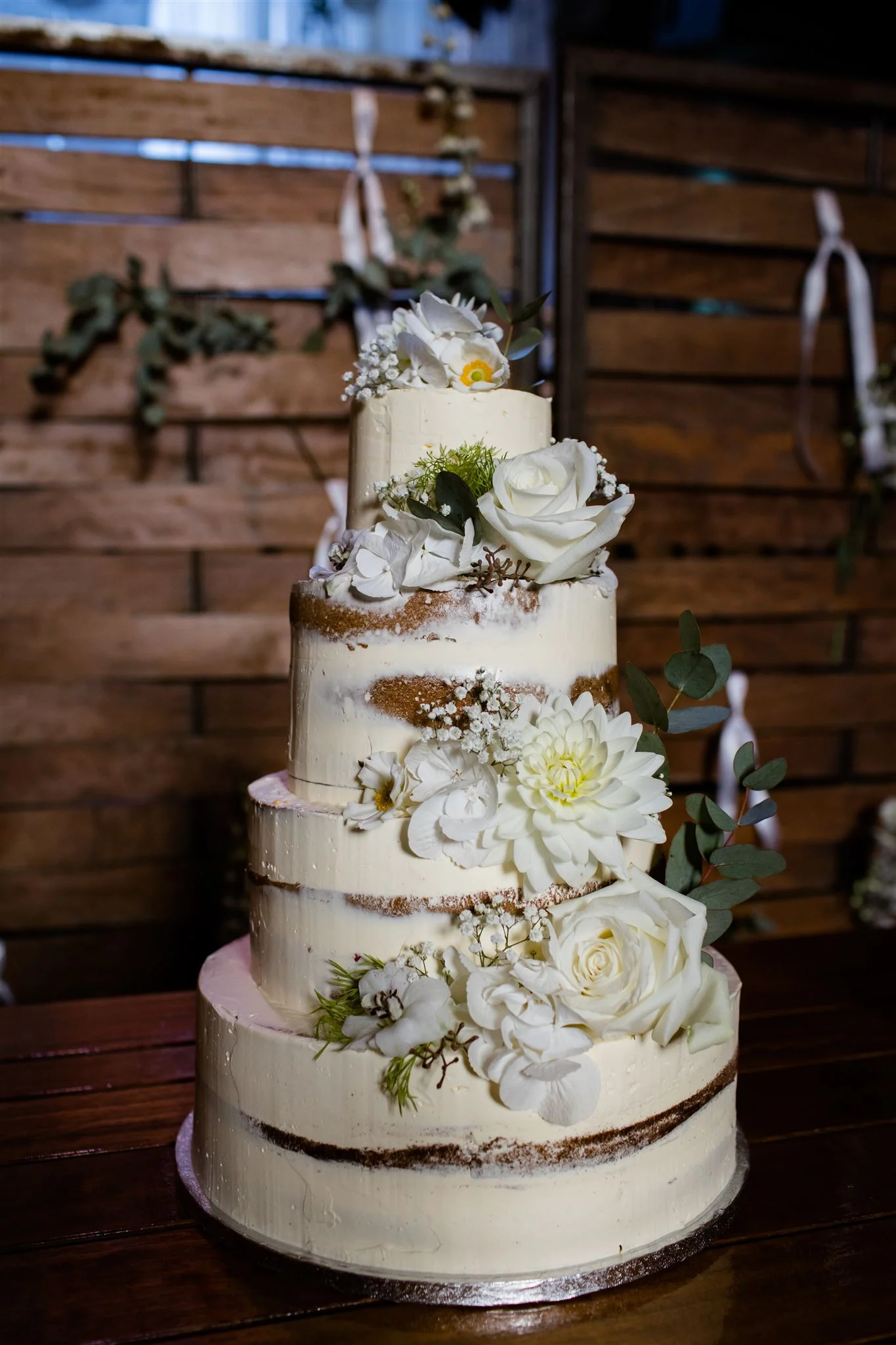 De bruidstaart van vierlagen in de kleur wit, met daarop bloemen verwerkt zoals witte rozen.